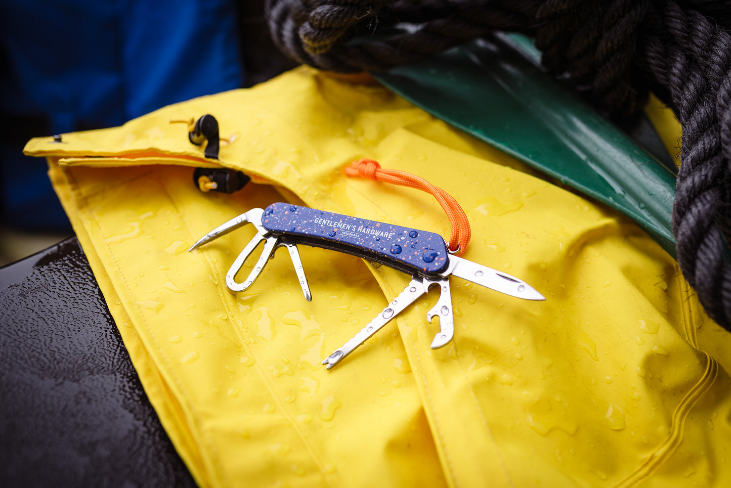 A Marine Multi-Tool with multiple tools extended sits on a yellow waterproof bag, both showing water droplets.