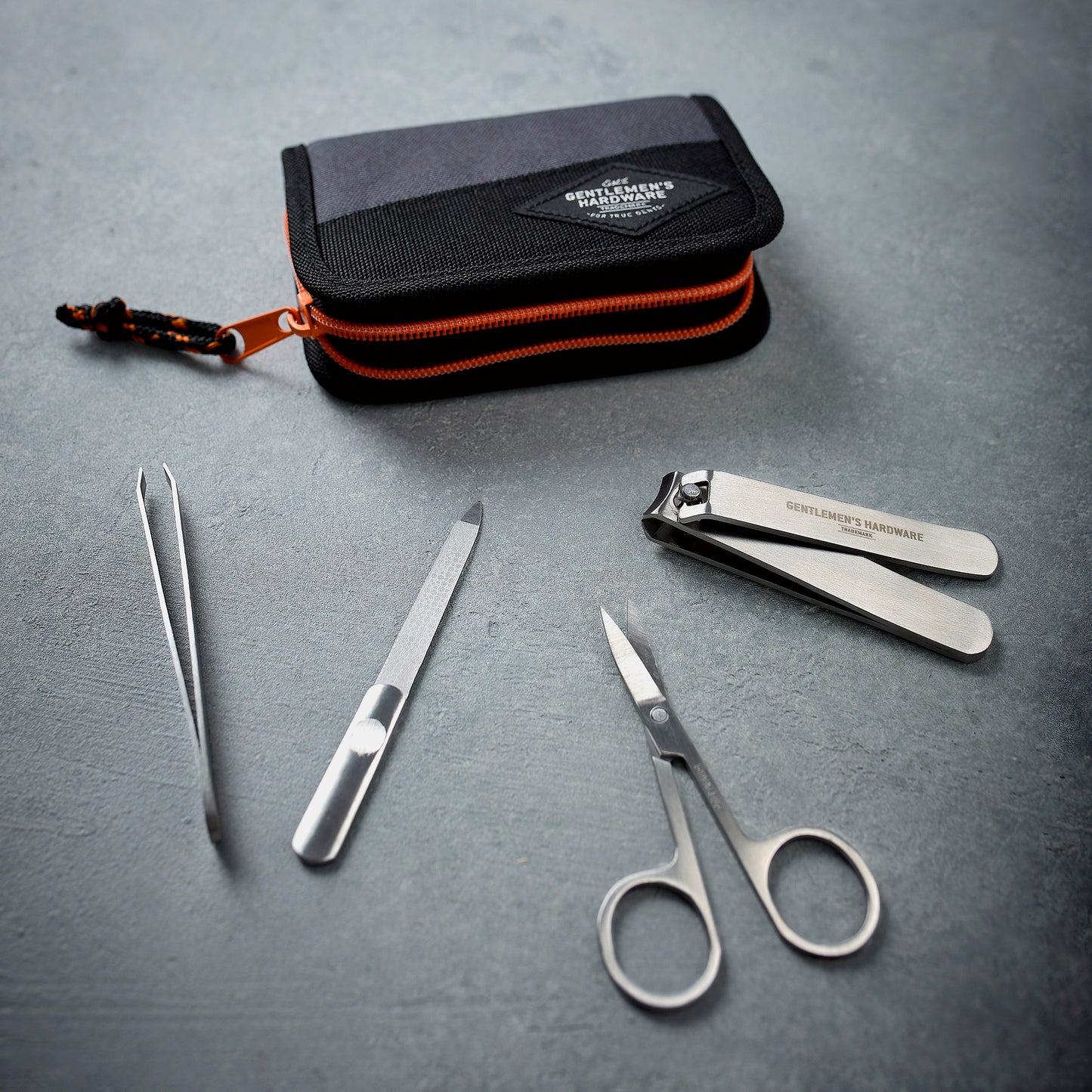 The Manicure Set includes stainless steel nail clippers, scissors, tweezers, and a nail file in a sleek zippered case, attractively displayed on a gray surface.