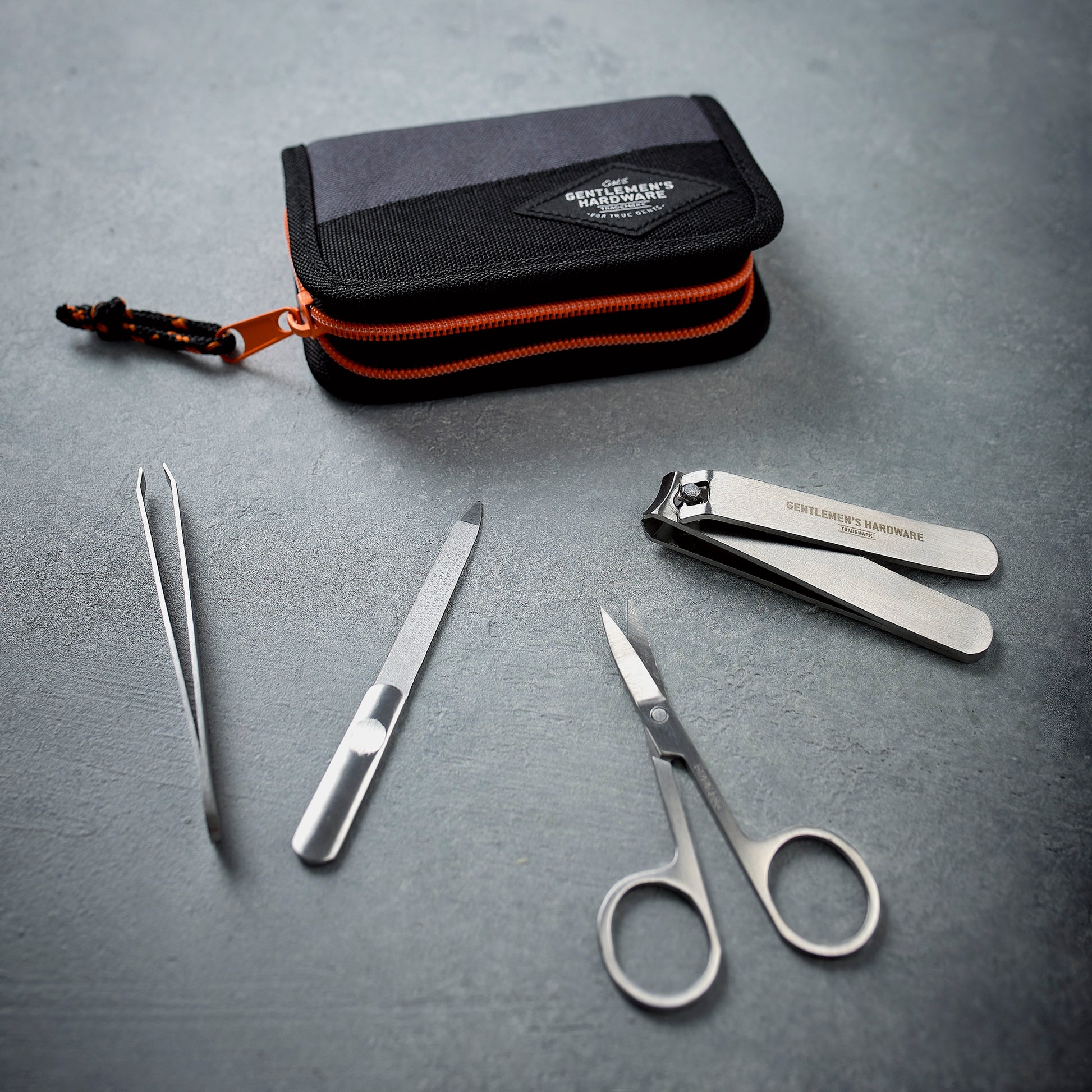 The Manicure Set includes stainless steel nail clippers, scissors, tweezers, and a nail file in a sleek zippered case, attractively displayed on a gray surface.