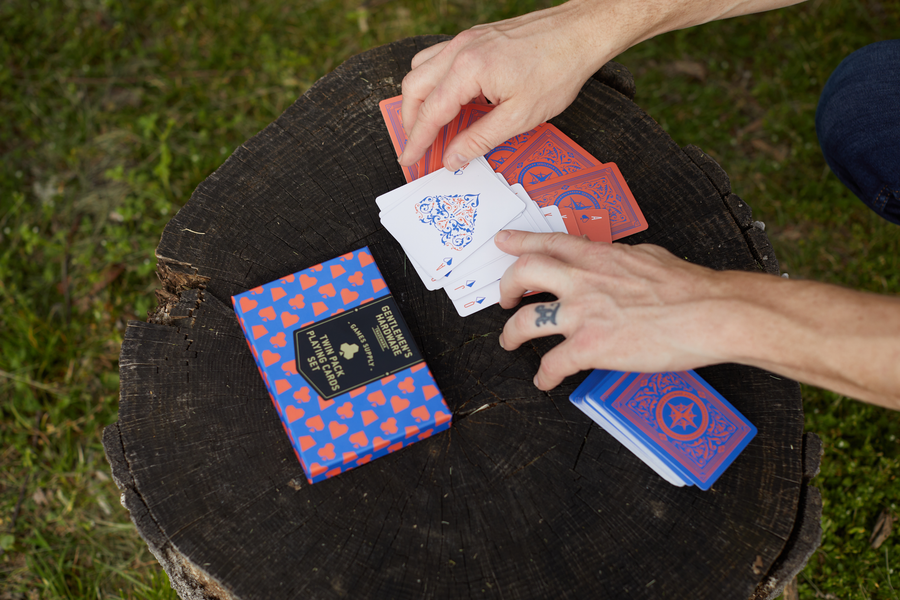 Gentlemen's Hardware Twin Pack Playing Cards on a log. 