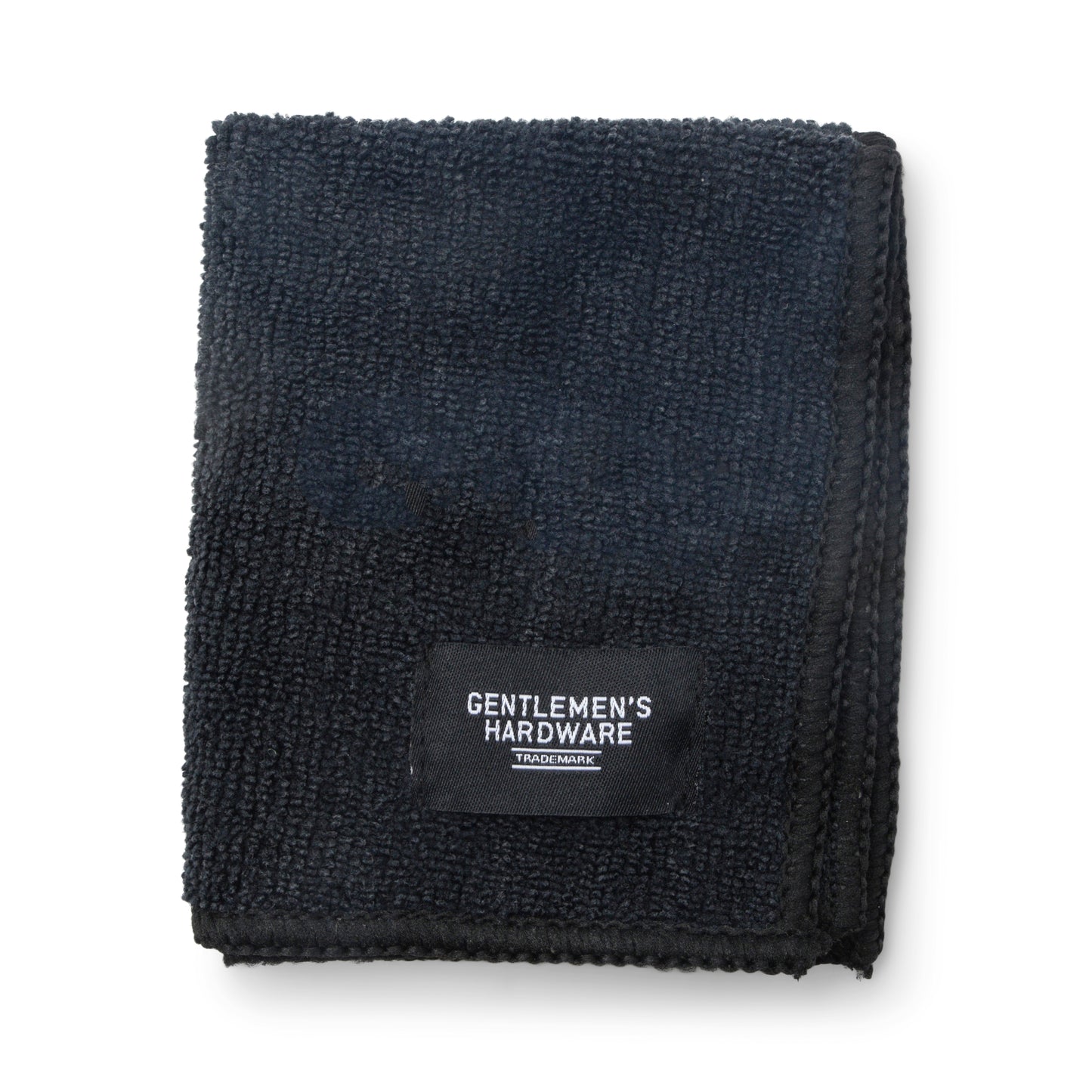 A neatly folded black microfiber cloth, featuring a Gentlemens Hardware label on one corner, from the Squeaky Clean Clean & Repair Kit, displayed against a plain white background.