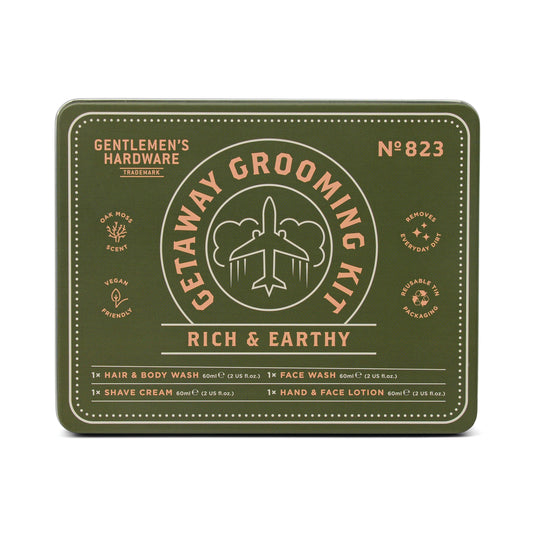 A green rectangular tin labeled Getaway Grooming Kit, by Gentlemen’s Hardware, showcases yellow and white travel-themed graphics—an essential grooming accessory for travelers.