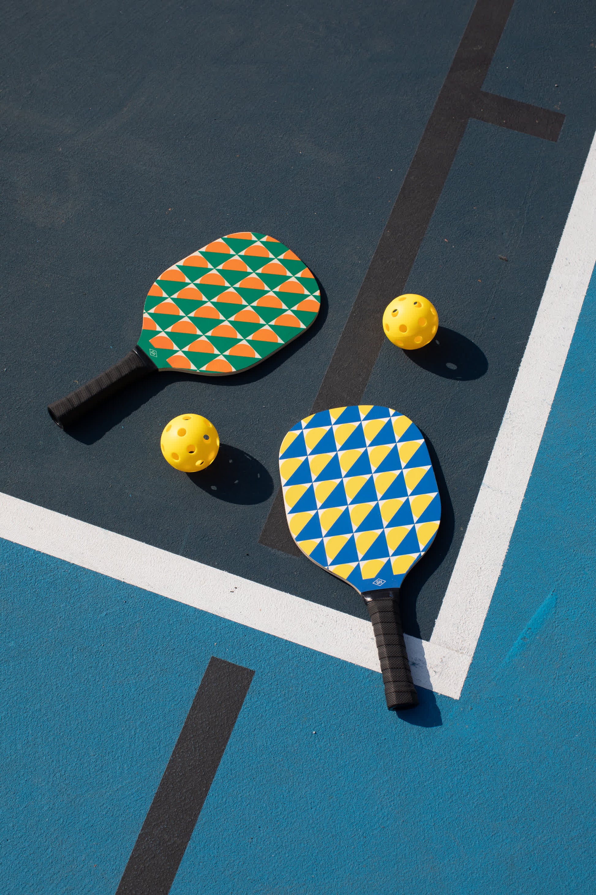 The Pickle Ball Set includes two colorful paddles and two yellow perforated balls, resting on an outdoor court—perfect for exciting games and friendly competition.