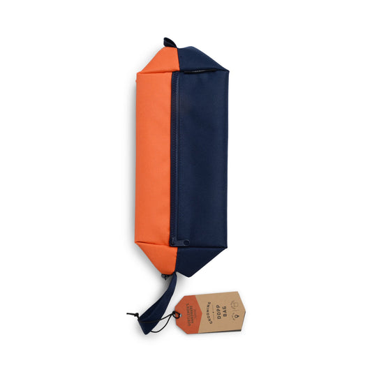 The Dopp Bag features orange and navy panels, a wrist strap, a brown tag, and an outer zip pocket for convenience.
