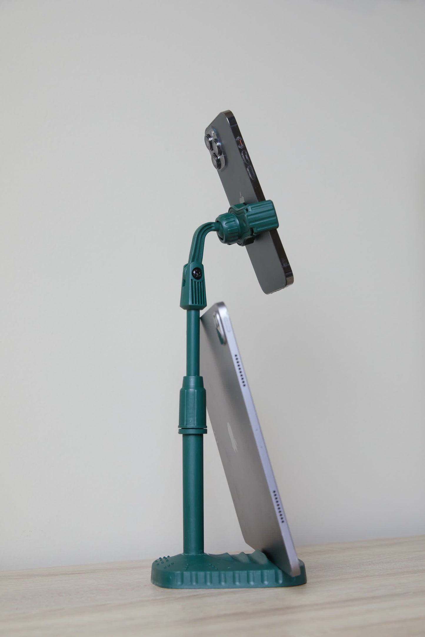 The Phone Tripod is a green desk companion that keeps your smartphone upright and supports your tablet at an angle on a light surface with a plain background.