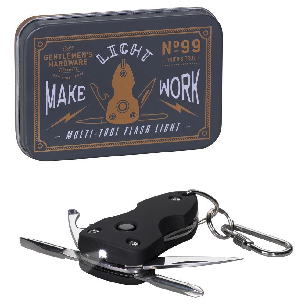 A rectangular metal tin labeled Gentlemens Hardware sits beside a Pocket Multi-Tool with Flash Light, featuring open stainless steel blades, an LED light, and a keychain attachment.