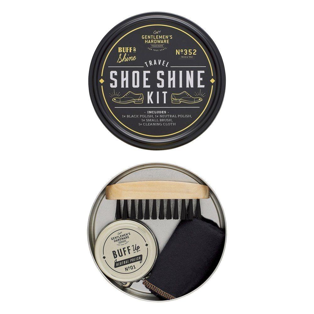 A round Travel Shoe Shine Tin with the lid off, showing a brush, shoe polish tin, and a neatly folded cloth arranged inside.