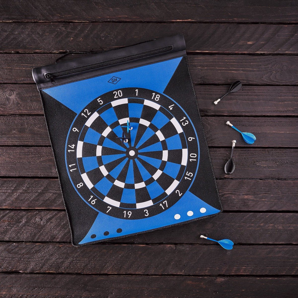 The Magnetic Dartboard Roll, in blue and black, comes with three blue darts—one in the bullseye and two beside the board—making it a sleek addition to any game room.