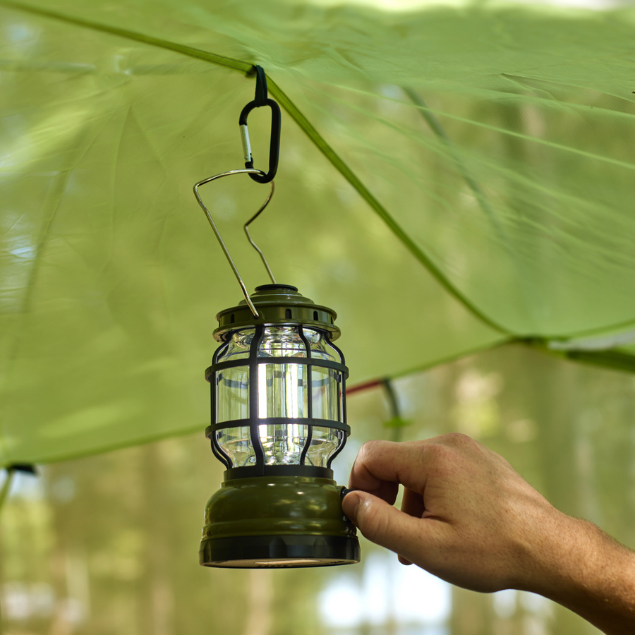 Camping Lantern hanging from carabiner attached to tent roof with a a hand adjusting the brightness