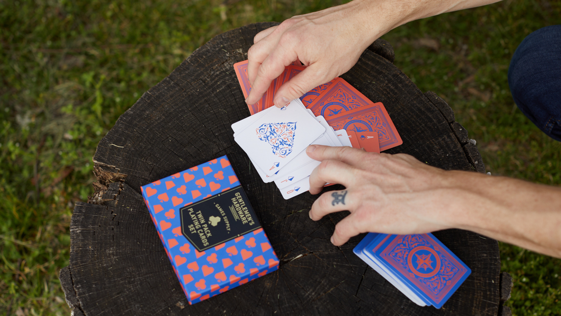 Two hands playing cards on a tree stump