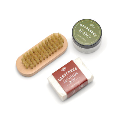 Exfoliating soap, hand balm, and scrub brush on white surface