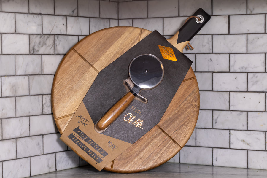Gentlemens's Hardware pizza cutter and serving board in the packaging in a kitchen