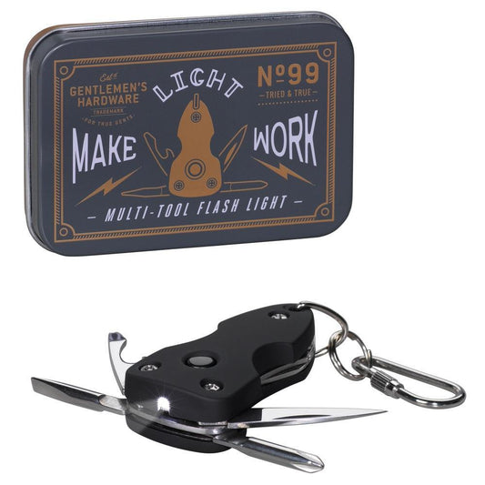 A rectangular metal tin labeled Gentlemens Hardware sits beside a Pocket Multi-Tool with Flash Light, featuring open stainless steel blades, an LED light, and a keychain attachment.