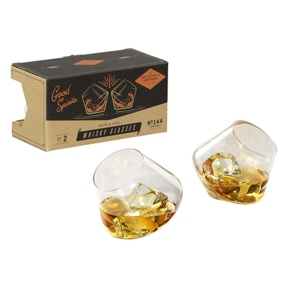 Two tilted Rocking Whiskey Glasses - Set of 2, filled with amber liquid and ice, are shown next to a cardboard box labeled Gentlemens Hardware Good Spirits Rock & Roll Whisky Glasses.