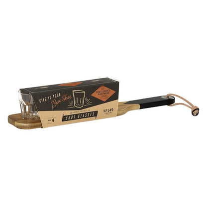 The Serving Paddle and Shot Glasses set includes four shot glasses on an acacia wood plank, partially wrapped in packaging that reads Give it your best shot and Gentlemens Hardware.