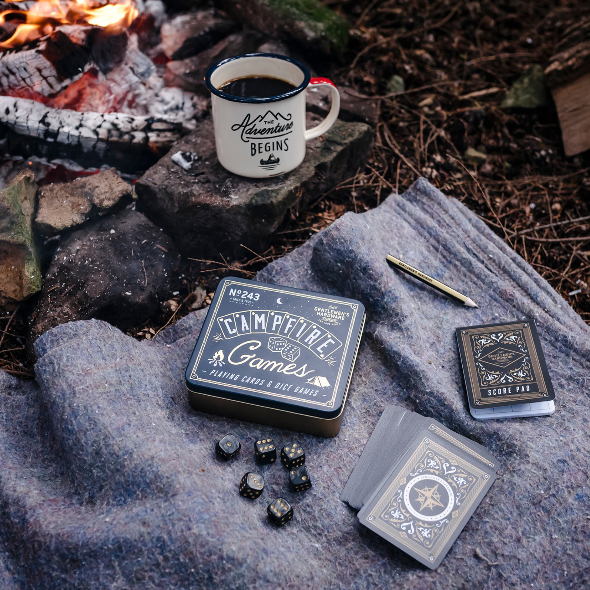 Campfire Games in front of fire with cards, dice, pencil, and score pad on blanket