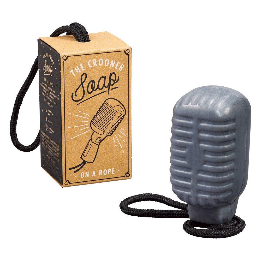 A gray, vegan Soap On A Rope - Crooner Oak Moss bar shaped like a vintage microphone with a black rope sits beside its box, featuring an oak moss scent.