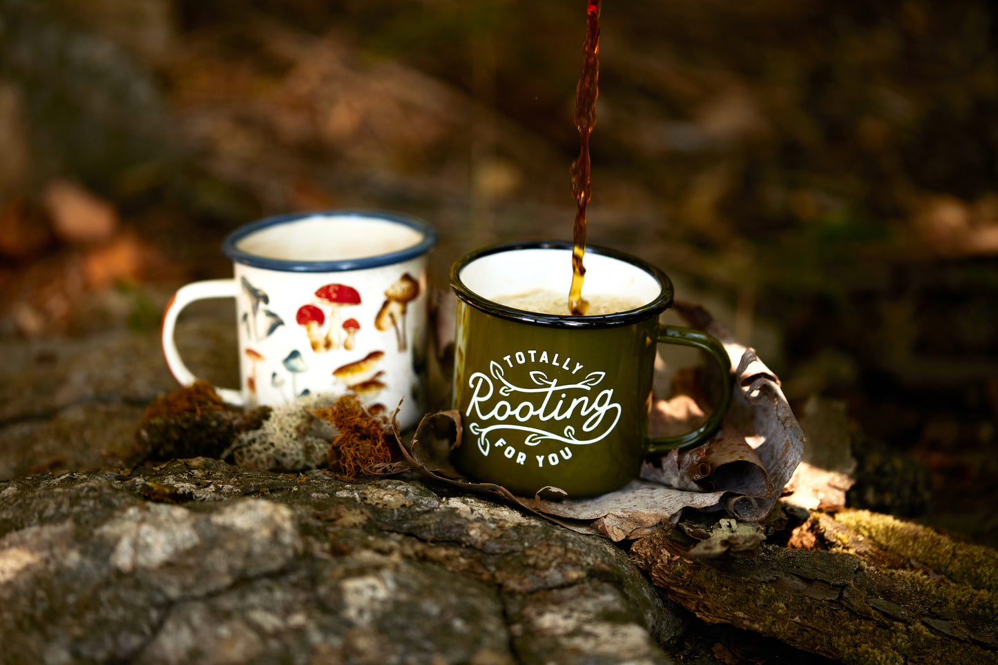 Enamel Mug - Mushroom 17 fl oz sitting next to Totally Rooting for you enamel mug on rocks in wilderness